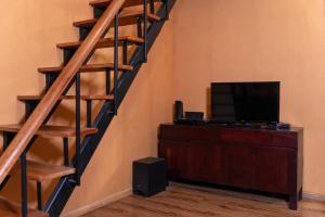 a living room with a wooden staircase with a television at The Cottage - Assure your Tickets for the Ella train journey in Ambawela