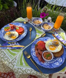 a table with plates of eggs and bacon and food at Villa Cape Garden Route in Wilderness