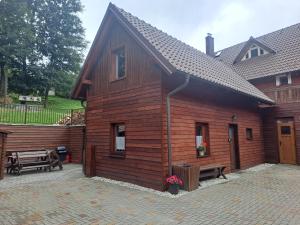 a wooden building with a bench and a table at Chaty Hrubý in Dolní Moravice