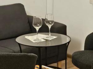 two wine glasses sitting on a table next to a couch at Rynek Staromiejski Apartment in Koszalin