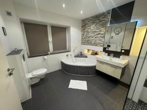 a bathroom with a tub and a toilet and a sink at BOHO Suite Tierra nähe Salzburg in Freilassing +33 photos