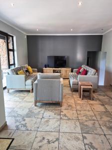 a living room with couches and a flat screen tv at Brett's Place in Warmbaths