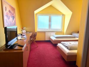 a room with two beds and a desk with a television at Hotel BernsteinSee in Bitterfeld