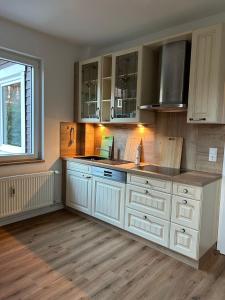 a kitchen with white cabinets and a wooden floor at Stadtblick Ferienwohnung in Braunlage