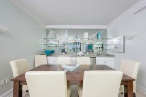 a dining room with a wooden table and white chairs at Phoenix on the Bay 1320 in Orange Beach