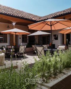 a patio with tables and umbrellas in front of a building at Centenario Hotel Boutique in Quetzaltenango