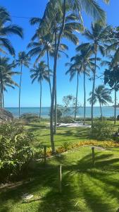 a group of palm trees on a beach with the ocean at Bangalô 12 in Porto Seguro