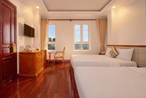 a hotel room with two beds and a table at Diamond Hotel in Da Lat