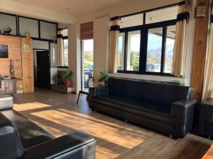 a living room with a black couch and windows at Dev Cottage in Mount Ābu
