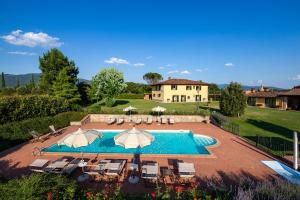 a pool with chairs and umbrellas in front of a house at Villa Farmi by MMega in Bibbiena