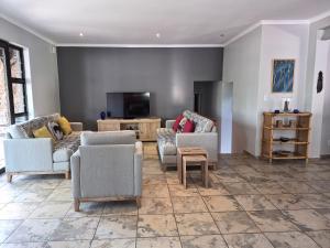 a living room with couches and a flat screen tv at Brett's Place in Warmbaths