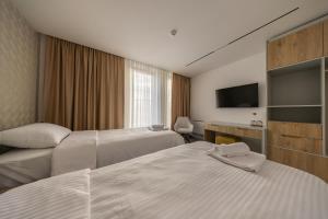 ein Hotelzimmer mit zwei Betten und einem Flachbildfernseher in der Unterkunft Hotel Opal Casa in Novi Pazar