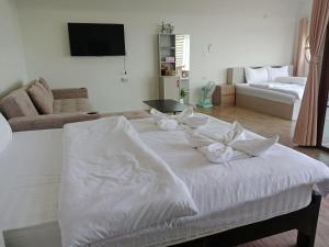 a white bed with white pillows on it in a living room at เดอะโดมโฮมสเตย์ ม่อนแจ่ม in Mon Jam