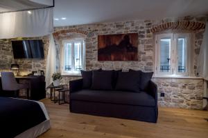 a living room with a couch and a stone wall at Murum Heritage Hotel in Split