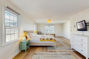 a white bedroom with a bed and a tv at Ledge on Green in Rockport