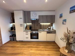 a kitchen with white cabinets and a sink at Appartement Steinbergrose in Leogang