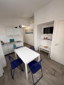 a white table and blue chairs in a room at Bilocale tranquillo e funzionale, ideale per soggiorni di lavoro in Vignola