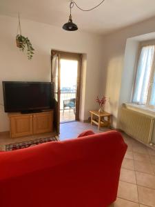 a living room with a red couch and a flat screen tv at Casa Marta in Lisignago