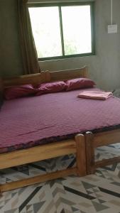 a bed with a wooden frame in a room with a window at Vitthala rukmini in Gokarna