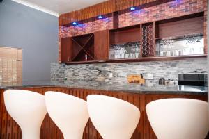 a bar with four white stools in front of a counter at Falcon Lodge (S) in Bela-Bela
