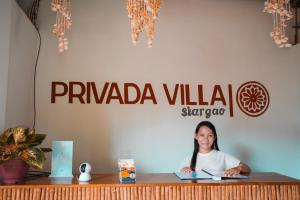 a woman sitting at a desk with a pen at Privada Villa Siargao in General Luna