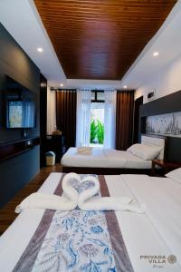 a bedroom with two beds with white sheets and a heart towel at Privada Villa Siargao in General Luna