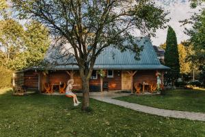 a girl sitting on a tree in front of a log cabin at Domek "Kasieńka" in Stronie Śląskie