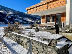 a house with a stone wall in the snow at Whiteberg Apartment in Schruns