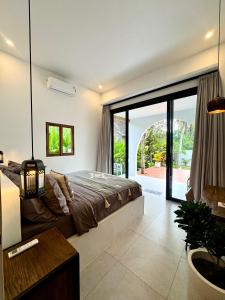 a bedroom with a bed and a large window at Casa De Made - Villas in Jembrana