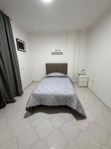 a white bedroom with a bed and a tiled floor at B&B Boffa in Buccino