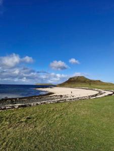 a beach with the ocean and a hill in the background at Skye Blue Bothy in Teangue