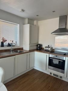 a kitchen with white cabinets and a sink and a stove at 2 Bed apartment- Laindon in Great Burstead