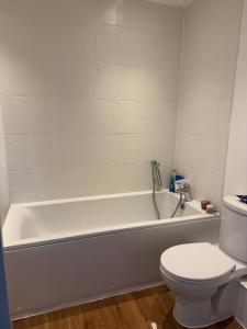 a bathroom with a white tub and a toilet at 2 Bed apartment- Laindon in Great Burstead