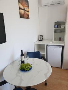 a white table with wine glasses and a bowl of grapes at Soba brez balkona in Stara Novalja +5 photos