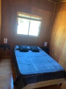 a bedroom with a blue bed with a window at L a N e g r a in Barra de Portezuelo