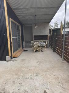 a patio with a table and chairs and a fence at L a N e g r a in Barra de Portezuelo
