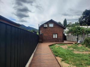 a brick house with a black fence next to a yard at Cabañas Entre Cerros y Ríos in Futaleufú