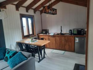 a living room with a table and a kitchen at Cabañas Entre Cerros y Ríos in Futaleufú