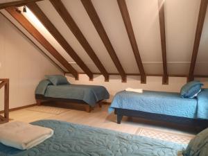 a room with two beds and a ceiling with beams at Cabañas Entre Cerros y Ríos in Futaleufú