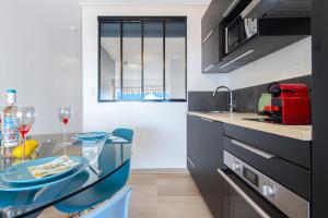 a kitchen with a glass table and blue chairs at Vue mer port de garavan in Menton