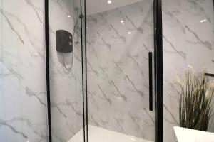 a bathroom with a shower with white marble at Modern 2 Bedroom Cottage Flat in Stenhousemuir +23 photos