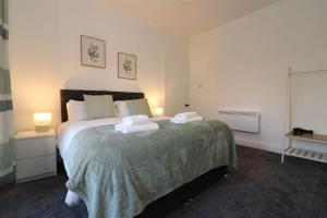 a bedroom with a large bed with two pillows at Modern 2 Bedroom Cottage Flat in Stenhousemuir