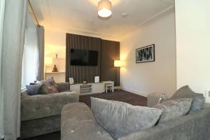 a living room with two couches and a flat screen tv at Modern 2 Bedroom Cottage Flat in Stenhousemuir