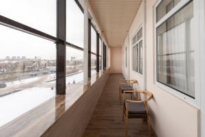 a corridor in a building with chairs and windows at Boutique Hotel Tomiris in Astana