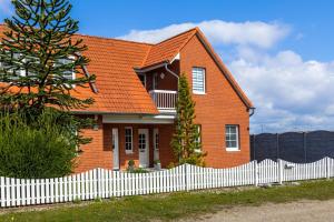 a red brick house with a white fence at Ferienwohnung Tina OG in Boltenhagen +13 photos