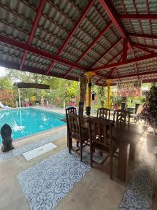 a patio with a table and chairs and a swimming pool at Baan Rim Tarn B&B in Takua Pa +56 photos