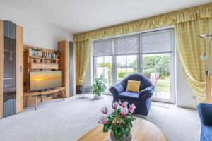 a living room with a blue chair and a television at Ferienwohnung Tina EG in Boltenhagen