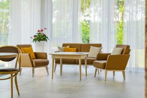 ein Wohnzimmer mit Stühlen, einem Tisch und einem Tisch in der Unterkunft Poznań West Hotel - Airport in Posen