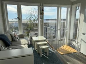 a living room with a couch and a table and windows at house with sea view in Varberg
