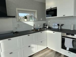 a kitchen with white cabinets and a sink and a window at house with sea view in Varberg